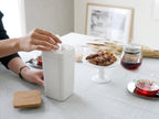 サラサデザインのウエットティッシュスタンド。ABS製の円筒形本体にシリコン蓋が付いた白色のテーブル用スタンドで、高さ約19cm。