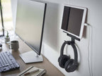 スチール製の【smart/スマート】ウォール スマートフォン＆ヘッドホンホルダーが壁に取り付けられ、スマートフォンとヘッドホンを整理整頓している様子