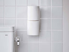 白色のスチール製トイレットペーパーホルダーが壁に取り付けられ、トイレットペーパーがセットされている様子