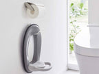 白いトイレの壁に取り付けられたタワーウォールトイレ用品収納フック。銀色のトイレットペーパーホルダー付き