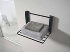 タワー折りたたみ棚がバスルームの石こうボード壁に設置されており、バスケットやトイレットロールホルダーが収納されている様子