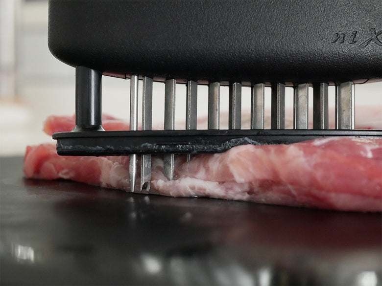 協和工業のニクサスプロ肉柔らかくする調理器具がまな板上で牛肉と豚肉をカットしている